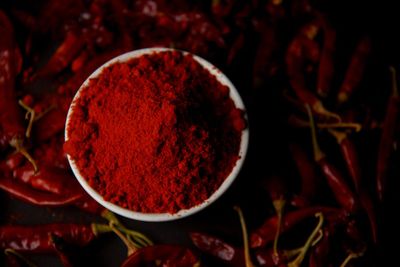 Vibrant red chilli powder in a bowl with dried whole chillies